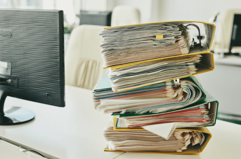 Pilha de documentos de requisição de backlog em uma mesa de trabalho aguardando resolução