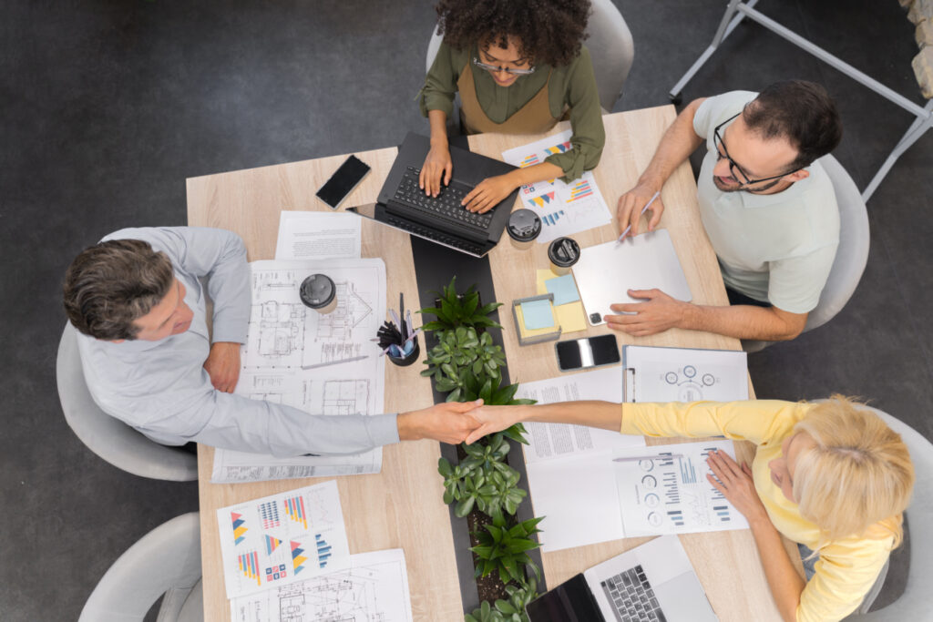 Equipes de diferentes empresas de desenvolvimento de software fazendo acordo de cocriação