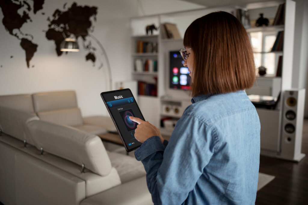 A imagem retrata uma pessoa utilizando um tablet em um ambiente residencial moderno e conectado, com um aplicativo de música aberto na tela. Essa cena ilustra como aplicativos movidos por inteligência artificial (IA) estão transformando a experiência do usuário em diferentes aspectos do cotidiano.